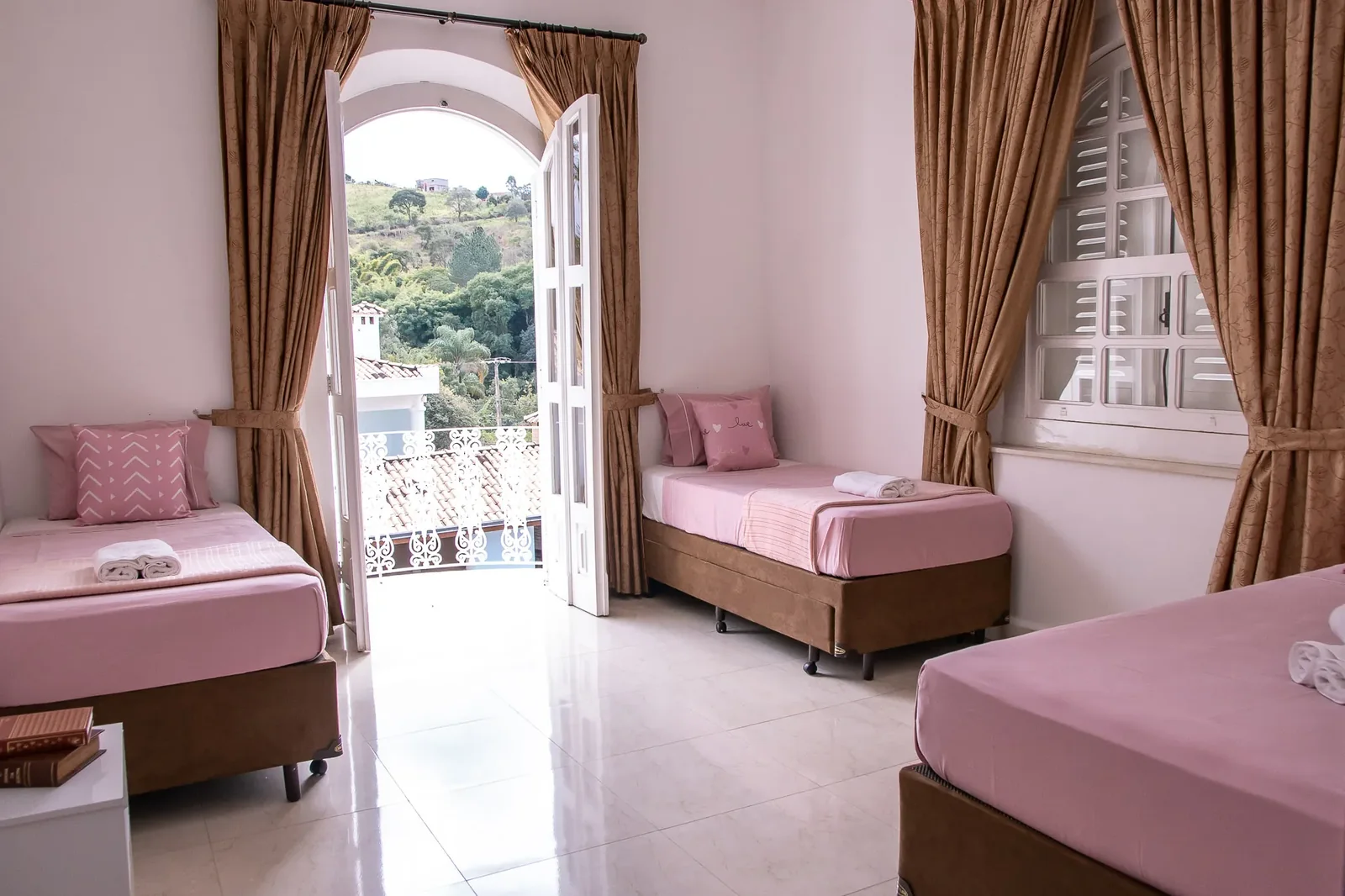 Quarto com duas camas de solteiro e portas de vidro para a varanda