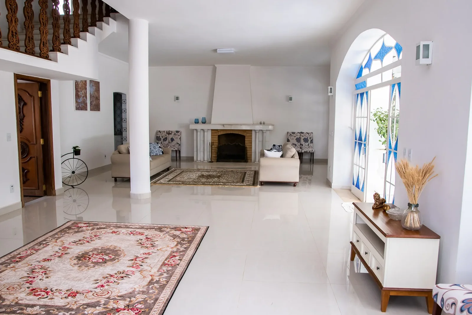 Sala de estar neoclássica com arcos, tapete e lareira