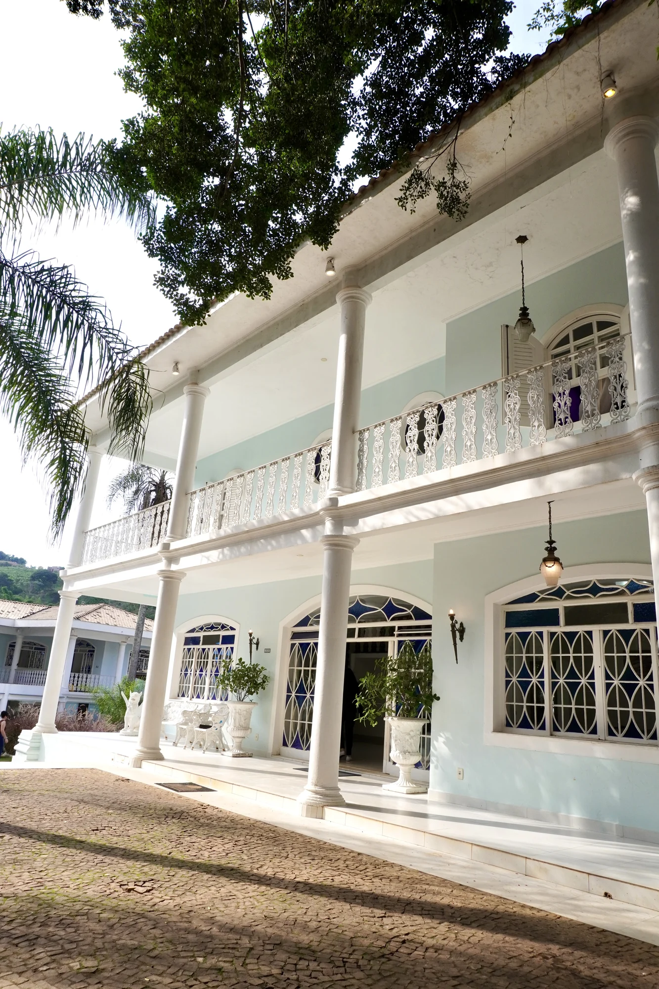Fachada branca do casarão neoclássico, com colunas, de dia
