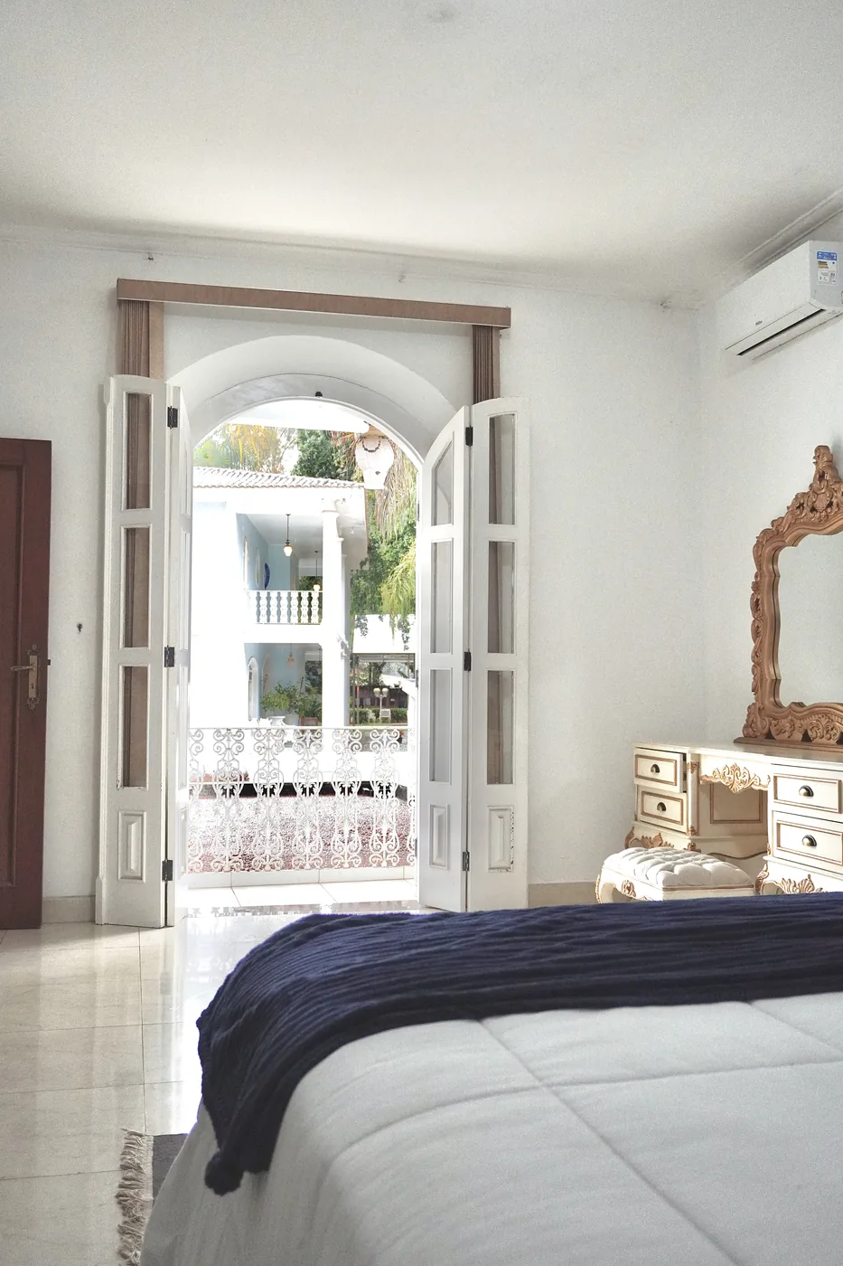 Quarto com portas francesas abertas para a varanda da Casa Sede