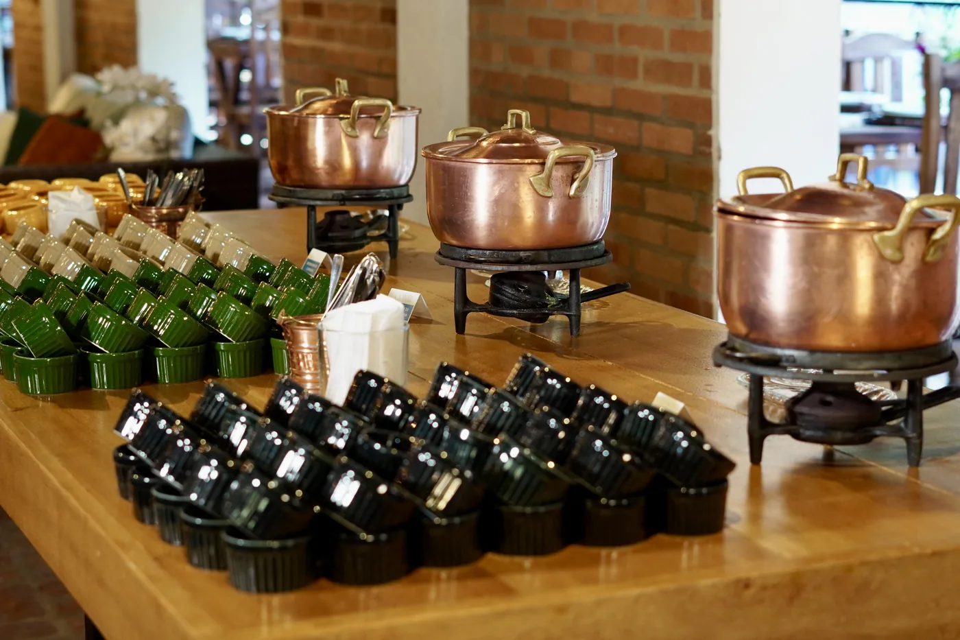 Buffet com chafing dishes de cobre e flores na mesa