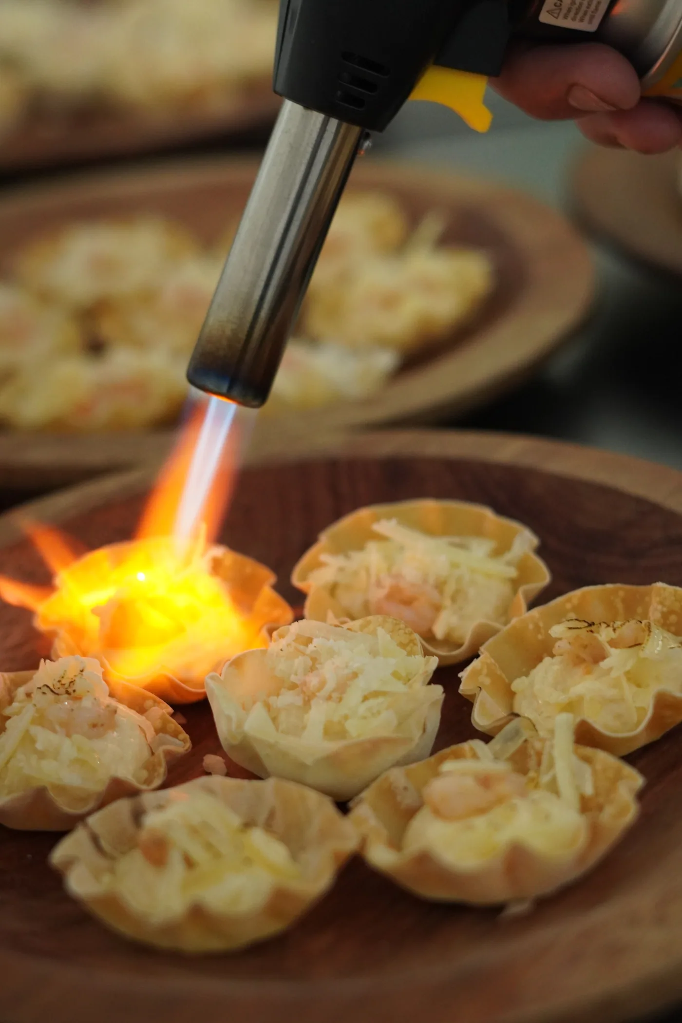 Canapés sendo flambados com maçarico, chama visível